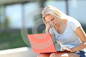 Frustrated student studying using laptop in a campus