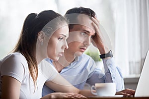 Frustrated surprised spouses looking at computer screen photo