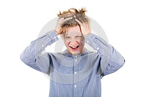 Frustrated teenage boy messing up and pulling his hair, hands to head, looking down shouting and screaming, isolated over white photo