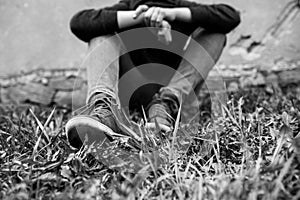 Frustrated teenage boy sitting near a crumbling wall at the correctional institute