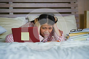 Frustrated and tired Asian Chinese university student woman feeling overwhelmed and stressed preparing exam studying with laptop