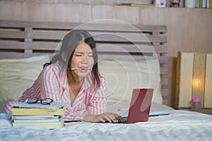 Frustrated and tired Asian Japanese university student girl feeling overwhelmed and stressed preparing exam studying with laptop