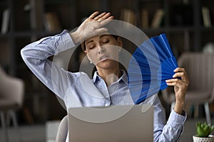 Frustrated unhappy young woman using paper fan.