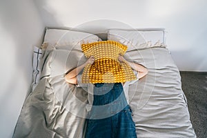 frustrated woman covering head with pillow, screaming feels furious exhausted exasperated laying on bed. mad irritated