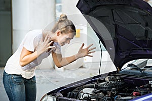 Frustrated Woman Looking At Broken Down Car Engine photo