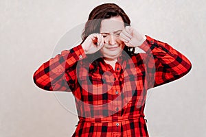 A frustrated woman in a red dress touches her face with her hands against