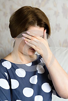 Frustrated woman sits and covering her face with her hand