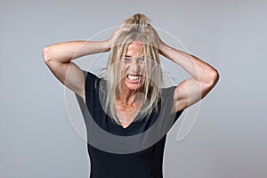 Frustrated woman tearing at her long blond hair