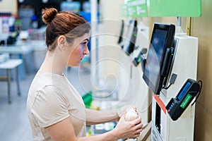 A frustrated woman uses a self-checkout counter. The girl does not understand how to independently buy groceries in the