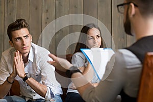 Frustrated worried young man listening to psychologist, couple c