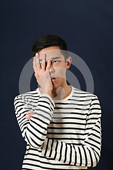 Frustrated young Asian man covering his face by palm
