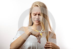 Frustrated young blonde woman having a problems with bad hair on white background
