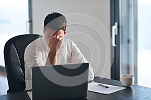 Frustrated young business man working on laptop computer at home