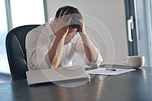 Frustrated young business man working on laptop computer at home