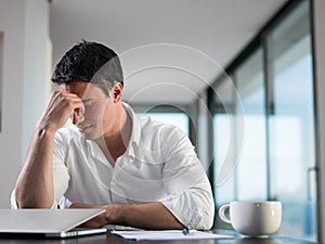 Frustrated young business man working on laptop computer at home