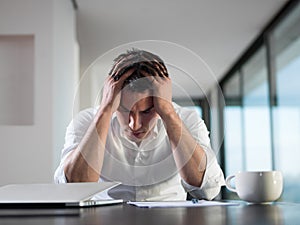 Frustrated young business man working on laptop computer at home