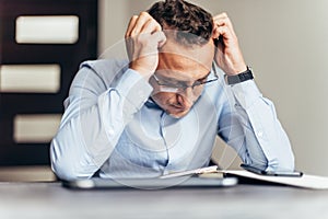 Frustrated young business man working on laptop computer at office