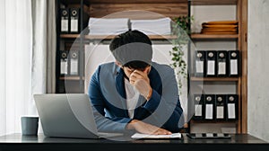 Frustrated young businessman working on a laptop computer sitting at his working place in office