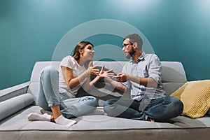 Frustrated young couple sitting on the couch and quarreling with each other