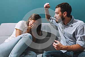 Frustrated young couple sitting on the couch and quarreling with each other