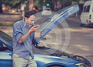 Frustrated young man calling roadside assistance after breaking down