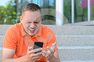 Frustrated young man gesturing at his mobile phone