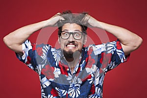 Frustrated young man in Hawaiian shirt pulling his hair photo