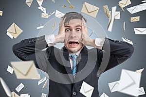 Frustrated young man and many falling envelopes. Many e-mails and spam concept.