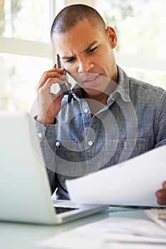 Frustrated Young Man On Phone Using Laptop At Home