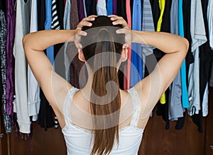 Frustrated young woman cannot decide what to wear from her close photo