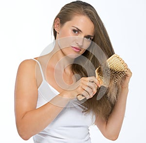 Frustrated young woman combing hair
