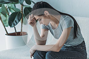 frustrated young woman in depression sitting on couch