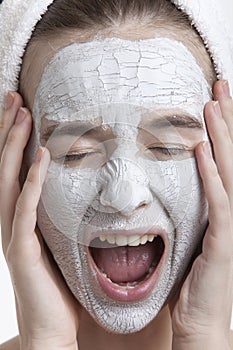 Frustrated young woman with face pack screaming against white background