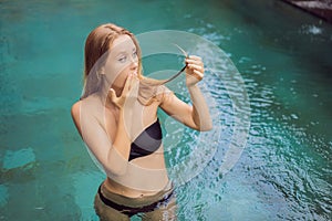 Frustrated young woman having a bad hair in the pool. Due to the fact that chemicals in the pool
