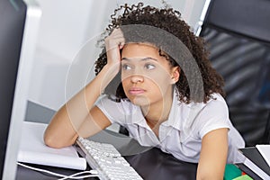 Frustrated young woman sat at computer sighing photo