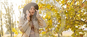 Frustrated young woman talking on phone standing in autumn park. Unhappy female talking over phone having problem. Copy