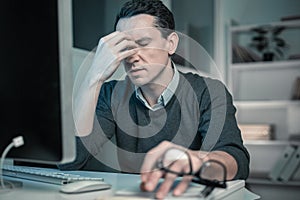 Frustrating man keeping eyes closed putting hand to face