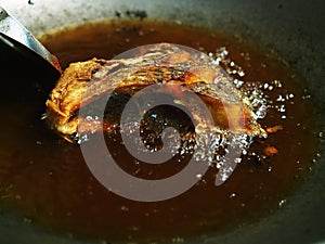 Fry fish in iron pan with hot oil by turner