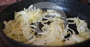 Fry onion in pan closeup. Fried onion calorie health benefits and harms