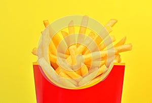 Frybox with french fries on a yellow background, close-up