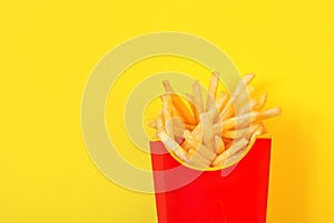 Frybox with french fries on a yellow background, copy space
