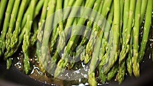 Frying asparagus in oil, close-up shot