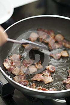 Frying bacon in oily pan