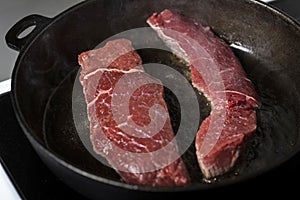 Frying beef steaks on a cast-iron pan