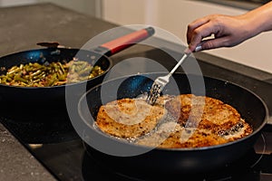 Frying Breaded pork on the pan and using a fork to turning it over