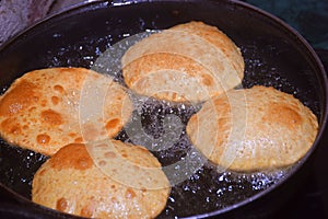 frying chapati(poori) on frying pan, boiling oil in frying pan with dark background, kitchen concept, selective focus