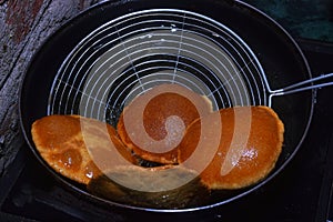 frying chapati(poori) with spoon on frying pan, boiling oil in frying pan with dark background, kitchen concept