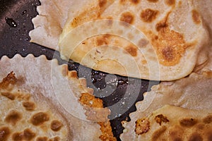 Frying chebureks in oil on a frying pan