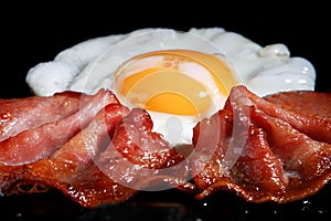 Frying egg and two bacon rashers photo