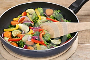 Frying food vegetables in cooking pan with spatula